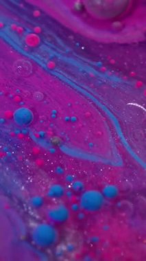 Dikey video. Boya maddesi. Akrilik kütle. Mor mavi karışımlı sıvı yağ akışı. Işıldayan renkli sanat kabarcığı emülsiyon akışı soyut arkaplanı bulanıklaştırır.