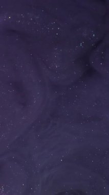 Dikey video. Buhar sıvısı. Kozmik akış. Violet ışıldayan pigment spirali suda çözünür. Parıldayan soyut mürekkep karışımı gece rengi bulanık arkaplan.