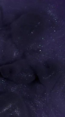 Dikey video. Duman patlaması. Duman boyası. Mor köpüklü suda siyah dalga pigmenti döküldü. Renk akışı boyası odaklanmış kozmik soyut arkaplan.