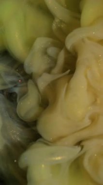 Dikey video. Bulut sıçraması. Köpüklü sıvı. Sarı yeşil parıltılı patlama boya akışı. Sanat sisi bulanık renk rengi su fantezi arkaplanı.