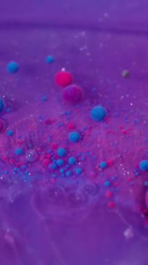 Dikey video. Kabarcık girdabı. Yüzen mürekkep. Pembe mor yağ damlaları ışıldayan parlak sıvılarda akıyor. Çoklu renk karışımı bulanık arkaplan.