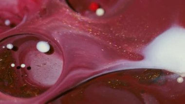 Parıldayan boya sıvısı. Mürekkep yağı suyu. Soyut akrilik zemin üzerinde yüzen kırmızı, beyaz, altın sarısı, yuvarlak, parlak, sıvı bir akış..