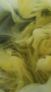 Dikey video. Duman akıntısı. Boyayla boyanmış. Beyaz sarı sıvı boya akışı. Sanat dumanı dalgası soyut bulanık siyah arkaplan karıştırma pigmenti.