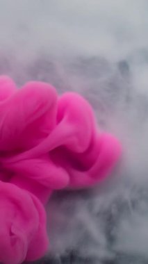 Dikey video. Duman akıntısı. Boyayla boyanmış. Beyaz pembe sıvı boya akışı. Sanat dumanı dalgası soyut bulanık siyah arkaplan karıştırma pigmenti.