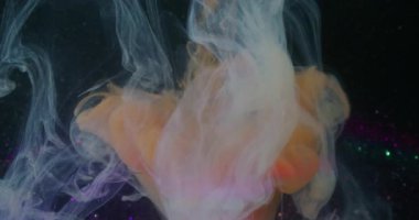 Boya damlası. Dönen sis. Odaklanmamış turuncu mavi mor simli kırık ampul soyut koyu siyah arkaplanda yüzüyor..