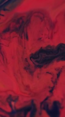 Dikey video. Renk sıvısı karışımı. Mermer boya. Soyut sanat üzerine odaksız kırmızı mavi su akrilik sıvı ıslak akış dokusu koyu siyah zemin.