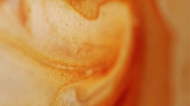 Işıldayan sıvı. Pırıl pırıl. Soyut akrilik zemin üzerine dökülen su lekelerinde çözünmüş sarı turuncu renkli boya..