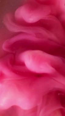 Dikey video. Mürekkep arkaplanı. Sıvı sıçraması. Bulanık pembe renkli su kıvrımlı sis akrilik parçacıklar koyu siyah soyutlama üzerinde sallanıyor.
