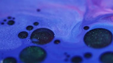 Akan damlacıklar. Parlak sıvı. Soyut arkaplanda yüzen mavi, mor, yuvarlak, boya yağı, kimyasal, diş minesi rengi..