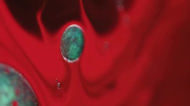 Dikey video. Köpüklü su. Çember mürekkep. Bulanık kırmızı mavi yağ yuvarlak sıvı koyu siyah sıçrama soyut akrilik arka planda yayılıyor.