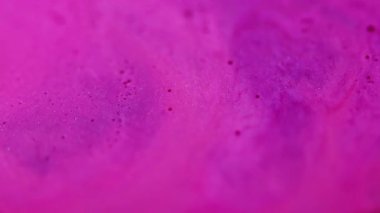 Karışım akışı. Akrilik pigment. Odaklanmamış pembe renkli parlak yuvarlak boncuk parçacıkları soyut kimyasal arka planda suda yüzen boya.