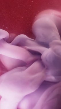 Dikey video. Arkaplanı boya. Karışık renk. Soyut akrilik dokuda yüzen sıvı içinde çözünmüş pembe su buharı girdabı..