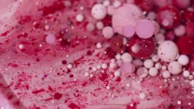Yuvarlak mürekkep suyu. Boya sıvısı. Odaklanmamış kırmızı pembe beyaz renkli ışıldayan partiküller soyut bokeh sanat arka planında yüzer..