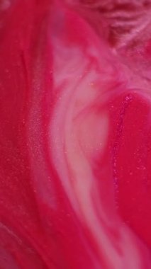 Dikey video. Parıldayan boya. Soyut mürekkep. Odaklanmamış kırmızı, mor renkli su parıltılı sıvı parçacıkları sanatın canlı arka planına dökülüyor..