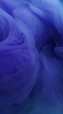 Dikey video. Dalga yayılıyor. Renk sıvısı. Odaklanamayan mavi sıvı girdap akrilik pigment buharı soyut koyu siyah arkaplan üzerinde yükseliyor.