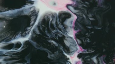 Boya lekeleri. Renk karışımı. Odaklanmamış kırmızı pembe sıvı koyu siyah lekeli akrilik doku soyut sanat arka planında büyüyor..