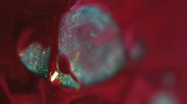 Dikey video. Soyut petrol. Kaleydoskop sanatı. Odaklanmamış kırmızı kırmızı boya damlası ıslak desen üzerine parlak su damlası koyu siyah arkaplan.