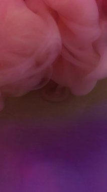 Dikey video. Dalga bulutu. Dönen duman. Soyut sanat arka planında süzülen ruhani dumanı karıştıran mor renkli akrilik su mürekkebi..