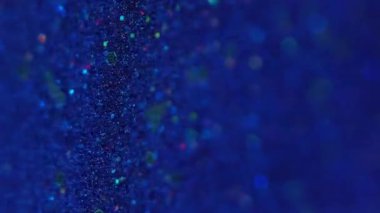 Dikey video. Bulanık pullar. Bokeh parçacıkları. Odaklanamayan mavi altın sarısı renkli parlak boya soyut arkaplana dökülüyor..