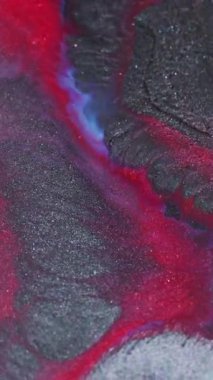 Dikey video. Görüntü sıçratma sanatı. Boya dokusu. Odaklanmamış kırmızı, mavi, gri, ıslak pigment. Soyut bokeh arka planında koyu siyah serpinti akışı..