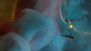 Buhar karışımı çözüldü. Kırık ampul. Parlayan çelengin üzerine renk bulutu dökülmüş. Kırmızı parıltılı, soyut, koyu arkaplanda mavi dumanlı boya var..