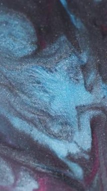 Dikey video. Görüntü sıvısı dökülmüş. Akrilik sıçrama. Odaklanmamış mavi kırmızı boya soyut arkaplanda yayılan parlak siyah parçacıklar..