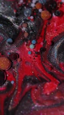 Dikey video. Yağ akışı. Sıvı arka plan. Yaratıcı koyu siyah soyutlama üzerinde yüzen parlak su yuvarlak dokusunda odaksız mavi renk mürekkebi.