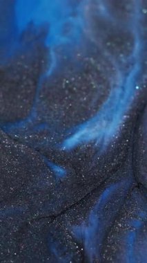 Dikey video. Mermer sıçraması. Renkli mürekkep dalgası. Odaksız mavi parlak pigment koyu siyah parçacıklar soyut akrilik canlı arkaplan üzerine dökülür.