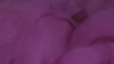 Parlayan duman. Bulanık boya dumanı. Mor simli partiküller sıvı dökülmesini soyut olarak harmanlarlar. Renkli bulut kıvrım suyu çözünür.