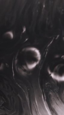 Dikey video. Boya lekesi. Sıvı emülsiyonu. Soyut yaratıcı sanat arka planında siyah beyaz damlalar yüzüyor..