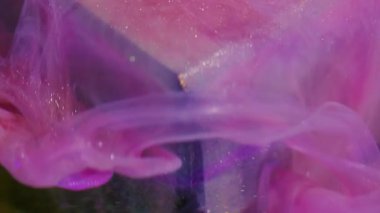 Yüzen boya. Odaklanmamış sanat sıçraması. Pembe parlak mor akış küpü. Suyun soyut arkaplanındaki parlak renk boyası çözülüyor.