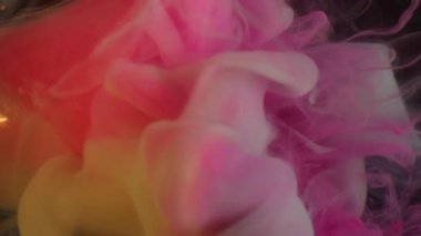 Boya girdabı. Odaklanmamış duman dalgası. Pembe turuncu gri sis karışımı mürekkep sıvıda. Işıldayan renk arkaplanında parlak bir çelenk.