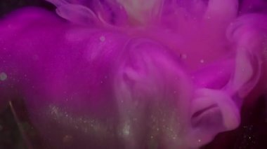 Su altı mürekkebi karışımı. Boya akışı. Odaklanamayan pembe parlak sıvı desen soyut koyu siyah bokeh arkaplan üzerindeki ampulü kırdı.