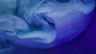 Mürekkep akışı. Görüntü pırıl pırıl akıyor. Sanat küresi üzerinde renk akrilik girdap karışımı. Parlak parçacıklar mavi menekşe sıvısı soyut arkaplan.