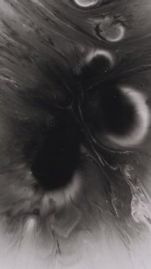 Dikey video. Mürekkep lekesi. Dökülen su. Odaklanamayan siyah beyaz akışkan kimyasal emülsiyon yuvarlak doku soyut akrilik arka plana dökülüyor..