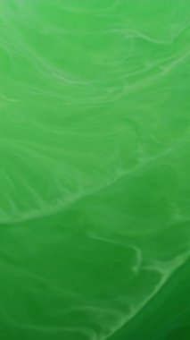 Dikey video. Mürekkep suyu dokusu. Boya damlası. Odaklanmamış yeşil renk soyut sanat akrilik yaratıcı arka planda sıvı parıltı akışı sıçratır.