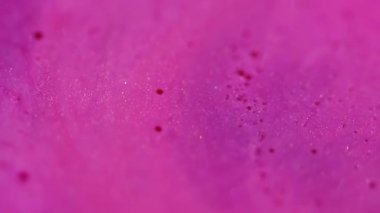 Islak pembe doku. Akrilik pigment. Odaklanmamış renk parlak yuvarlak boncuk parçacıkları soyut kimyasal arka planda suda yüzen boya.