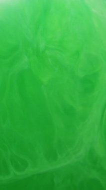Dikey video. Mürekkep sıvısı akışı. Boya jeli. Odaklanamayan yeşil renk soyut sanat akrilik ıslak yaratıcı arka plana su emülsiyon dokusu sıçratır.