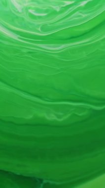 Dikey video. Boya sıvısı lekeleri. Emülsiyon jeli. Odaklanmamış yeşil renkli sıçrama damla su kıvılcım dokusu soyut sanat arkaplanında akıyor.