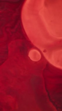 Dikey video. Sıvı leke. Lekeli yağ arka planı. Odaklanmamış pembe renkli su sıçraması soyut koyu siyah dokuda yuvarlak akış sıvısı..