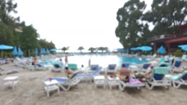 Konukların lüks bir tatil köyünde uzanıp yüzdüğünü dikkatsiz bir şekilde gördüm. Gezginler yaz tatilinin tadını çıkarırken güneşleniyorlar.