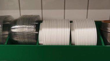 Paketleme malzemelerini düzgünce yerleştir. Kahve servisi için kağıt bardaklar, plastik kapaklar ve karton kollar hazır.