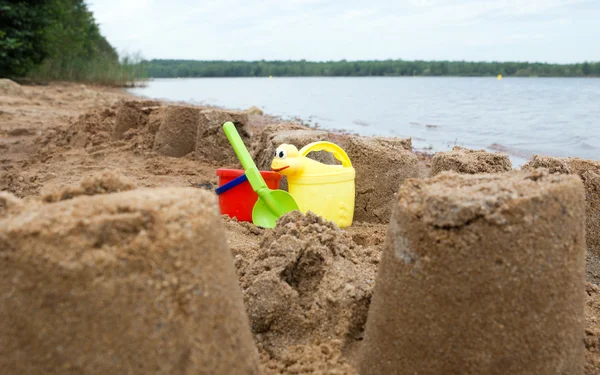 Castillo de arena con juguetes de arena en el agua — Foto de Stock