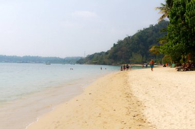 Grup yolcusu Koh Chang Tayland sahilinde güneşlenerek yürüyor.