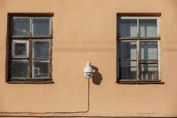 security camera on the house. two windows and video surveillance on the wall of the building