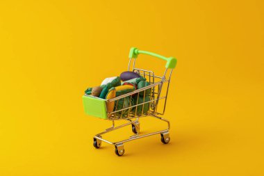 Sarı arka planda yemek için sepetteki oyuncak sebzeler.