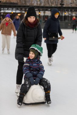 Anne ve oğlu buz pateni pistinde kayıyor.