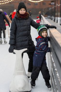 Anne ve oğlu buz pateni pistinde kayıyor.