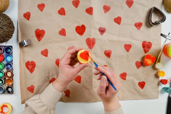 heart shaped potato stamp on craft paper. The process of decorating a gift for Valentines Day. Getting ready for the celebration on February 14th.
