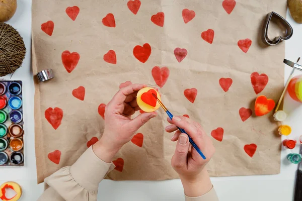 Sello de patata en forma de corazón en papel artesanal. El proceso de decorar un regalo para el Día de San Valentín. Preparándose para la celebración del 14 de febrero. — Foto de Stock